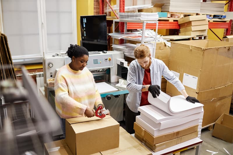 Two people packaging print materials for shipping